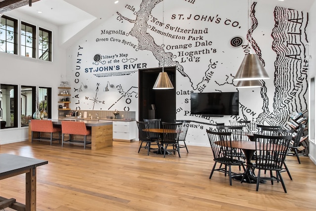 dining area with a towering ceiling, light hardwood / wood-style flooring, and sink