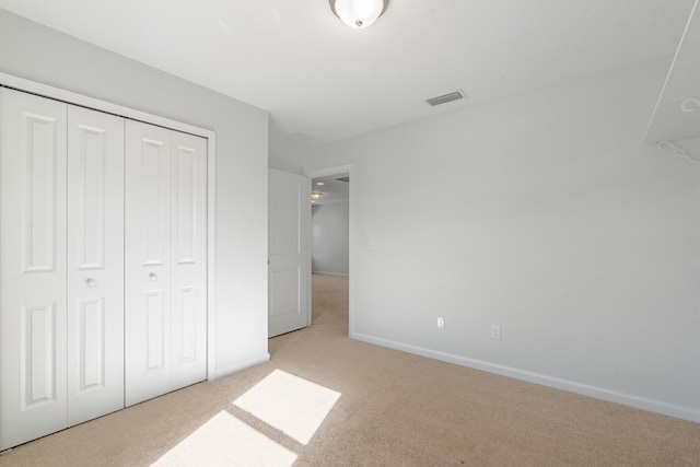 unfurnished bedroom with light carpet and a closet