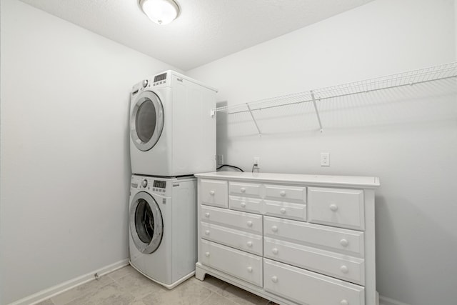 washroom featuring laundry area, baseboards, and stacked washer and clothes dryer