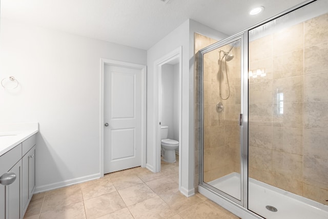 full bathroom featuring a stall shower, baseboards, vanity, and toilet