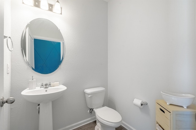 bathroom featuring baseboards, a sink, and toilet