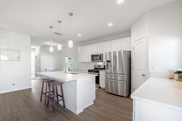 kitchen featuring sink, stainless steel appliances, pendant lighting, a breakfast bar, and white cabinets