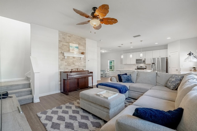 living area with light wood-style flooring, recessed lighting, visible vents, baseboards, and stairs