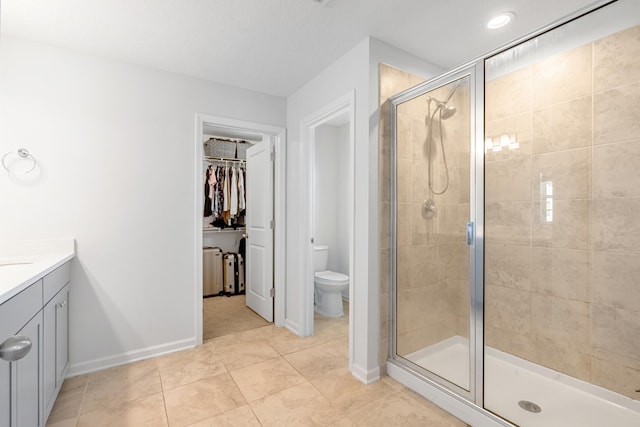 full bath featuring baseboards, toilet, a spacious closet, vanity, and a shower stall