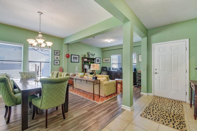 dining room featuring a healthy amount of sunlight, a textured ceiling, and an inviting chandelier