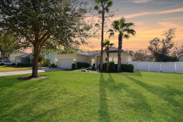 ranch-style home with stucco siding, fence, a garage, driveway, and a front lawn