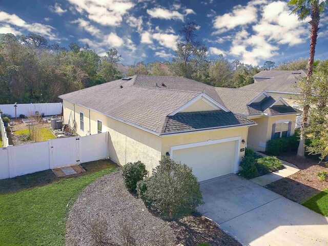 view of front of home with a garage, driveway, roof with shingles, fence, and stucco siding