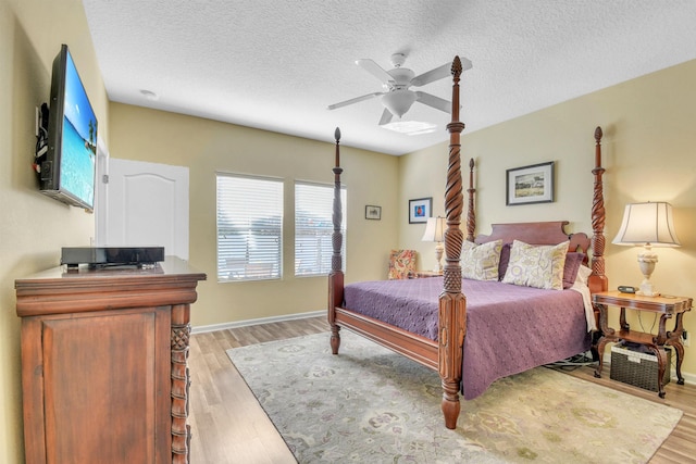 bedroom featuring a textured ceiling, light wood finished floors, a ceiling fan, and baseboards