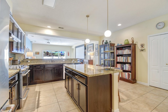 kitchen with a peninsula, dark brown cabinetry, stainless steel range with gas cooktop, and pendant lighting