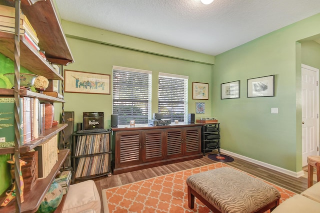 office area with a textured ceiling, baseboards, and wood finished floors