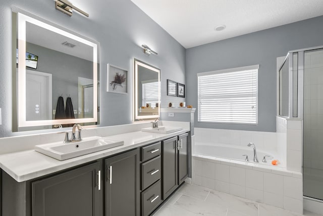 full bathroom featuring marble finish floor, double vanity, a sink, and a bath