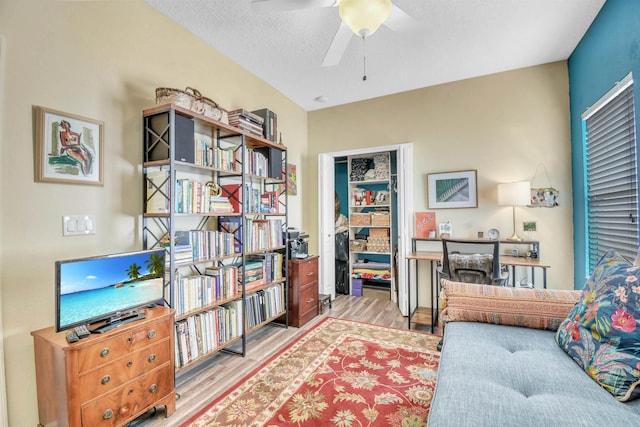 interior space with a ceiling fan, a textured ceiling, and wood finished floors