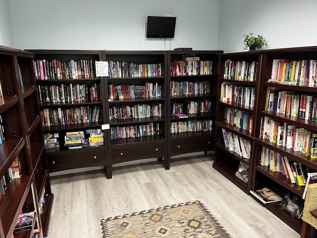 living area with wall of books and light wood-style flooring