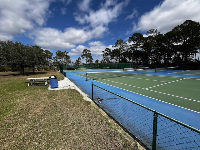 view of tennis court featuring a yard and fence