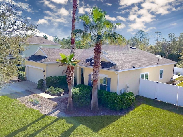 view of front of property featuring driveway, a front yard, fence, and stucco siding