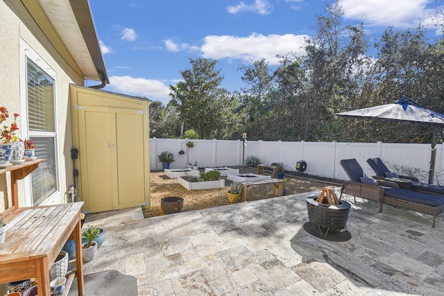 view of patio / terrace with an outdoor fire pit, a fenced backyard, a vegetable garden, and a storage shed