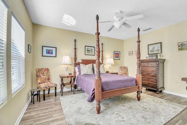 bedroom with multiple windows, a textured ceiling, and light wood finished floors