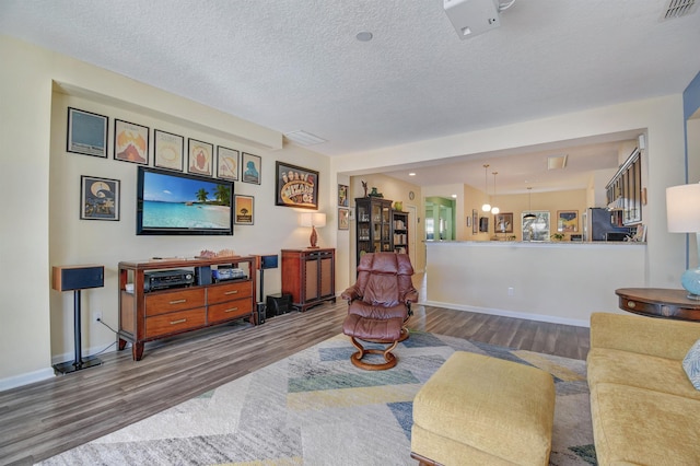 living room with visible vents, a textured ceiling, baseboards, and wood finished floors