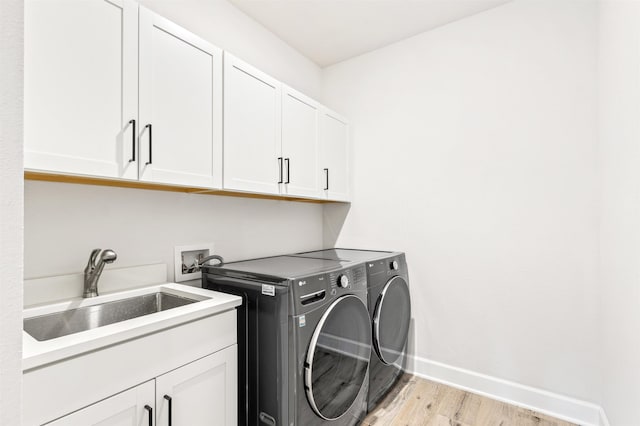 washroom with cabinets, washer and dryer, sink, and light hardwood / wood-style floors