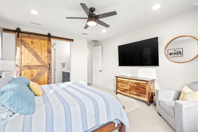 carpeted bedroom with ceiling fan, a barn door, and ensuite bath