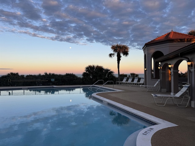 pool at dusk featuring a patio area