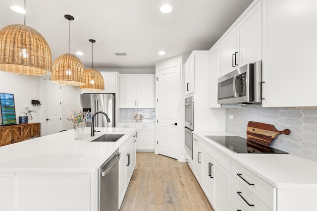 kitchen with sink, white cabinetry, stainless steel appliances, a center island with sink, and decorative backsplash