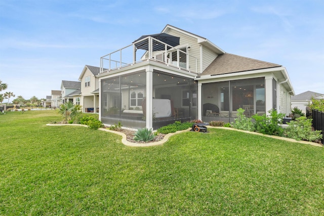 rear view of house featuring a lawn, a sunroom, and a balcony