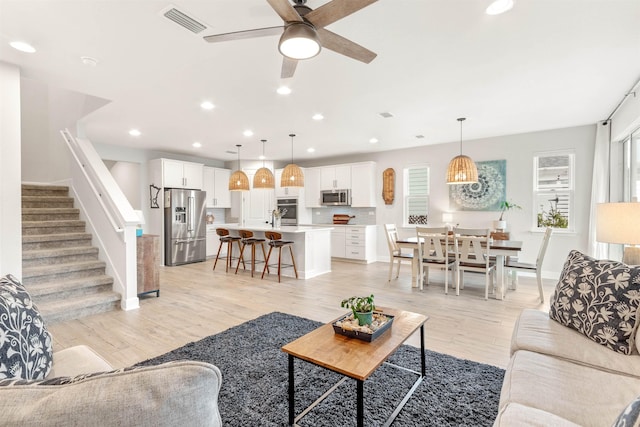 living room with ceiling fan, sink, and light wood-type flooring