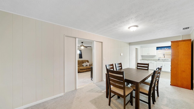 carpeted dining space with ceiling fan and a textured ceiling