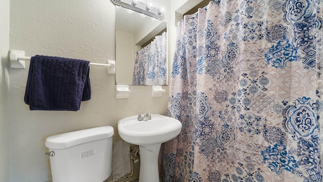 bathroom with a shower with shower curtain and toilet