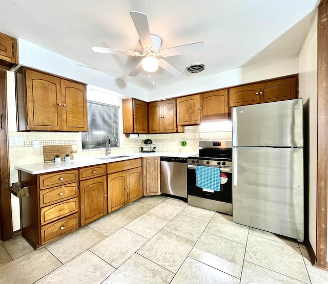 kitchen featuring brown cabinets, light countertops, visible vents, appliances with stainless steel finishes, and a sink