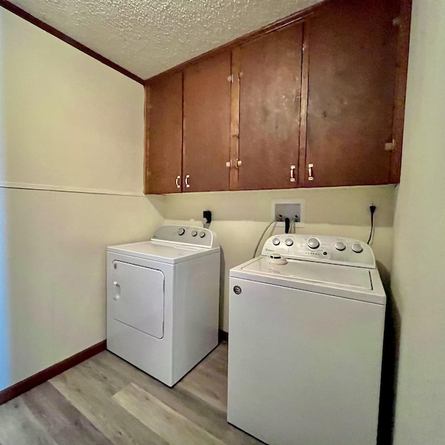 laundry room with cabinets, separate washer and dryer, a textured ceiling, and light wood-type flooring