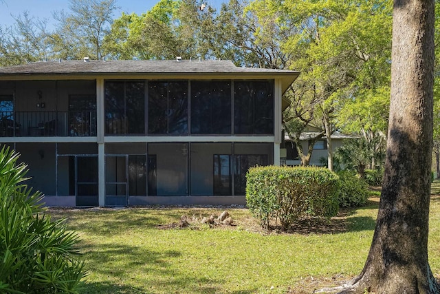 rear view of house featuring a yard and a sunroom