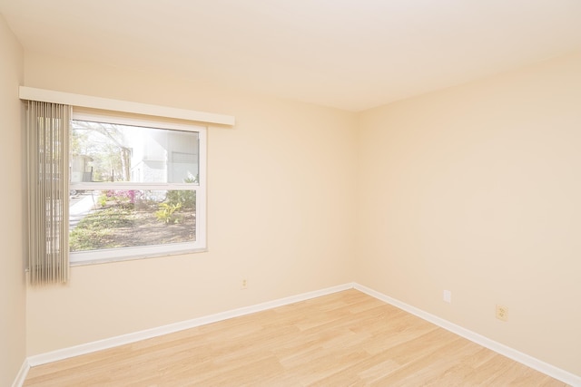 spare room with plenty of natural light, baseboards, and light wood-type flooring