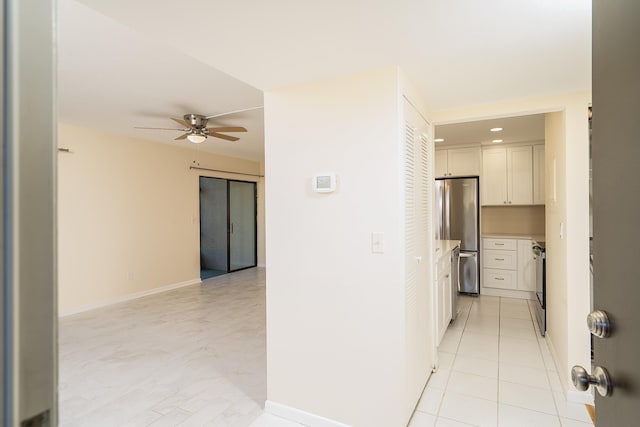 hallway with light tile patterned flooring and baseboards