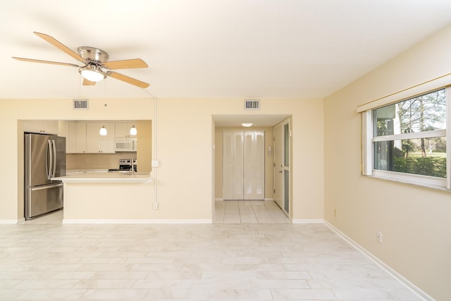 unfurnished living room featuring visible vents, baseboards, and a ceiling fan