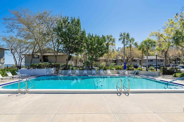 pool with a residential view, a patio, and fence