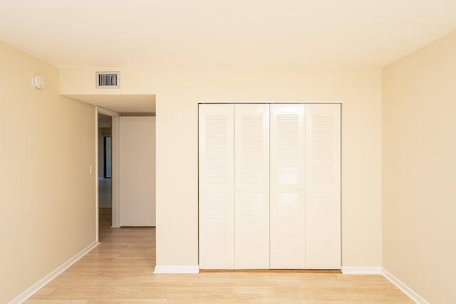 unfurnished bedroom with light wood-style flooring, visible vents, baseboards, and a closet