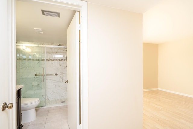 bathroom featuring a marble finish shower, baseboards, toilet, and wood finished floors