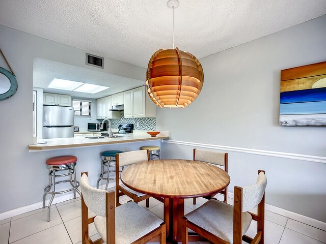 dining space with sink, light tile patterned floors, and a textured ceiling