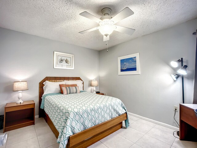 bedroom with a textured ceiling, ceiling fan, and light tile patterned flooring