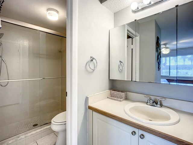 bathroom featuring vanity, ceiling fan, tile patterned flooring, toilet, and a shower with shower door