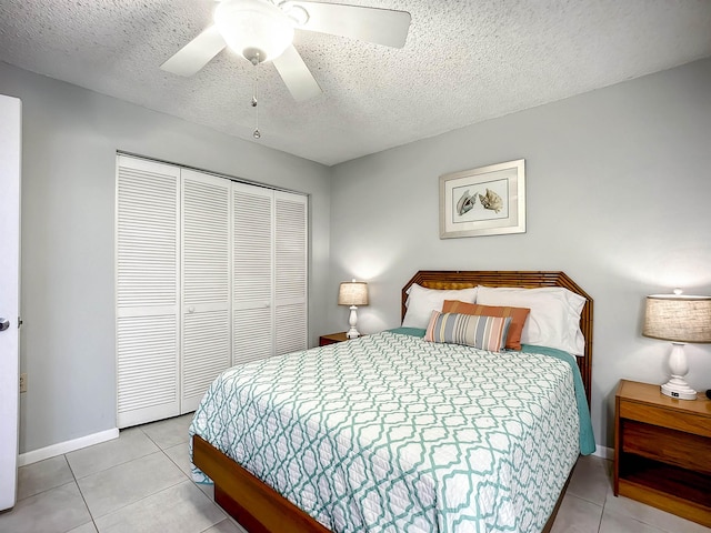 bedroom featuring a textured ceiling, a closet, ceiling fan, and light tile patterned flooring