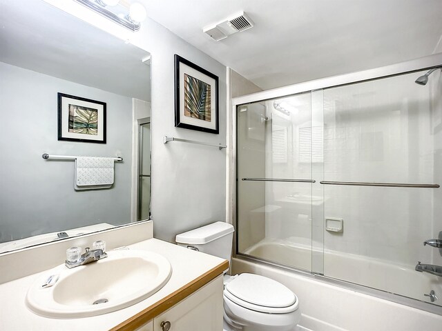 full bathroom featuring shower / bath combination with glass door, vanity, and toilet