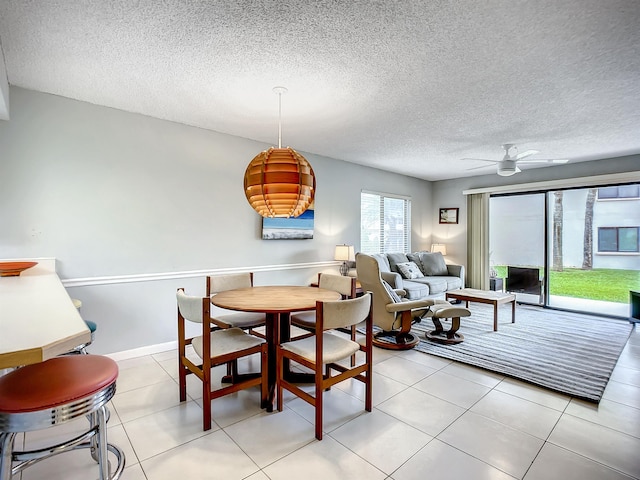 dining space featuring ceiling fan, light tile patterned floors, and a textured ceiling