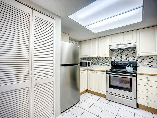 kitchen featuring decorative backsplash, light tile patterned flooring, white cabinetry, and appliances with stainless steel finishes