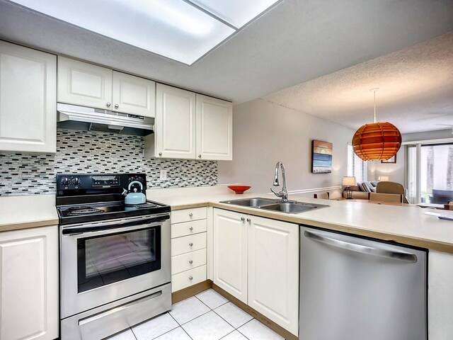 kitchen with kitchen peninsula, stainless steel appliances, sink, white cabinets, and light tile patterned flooring