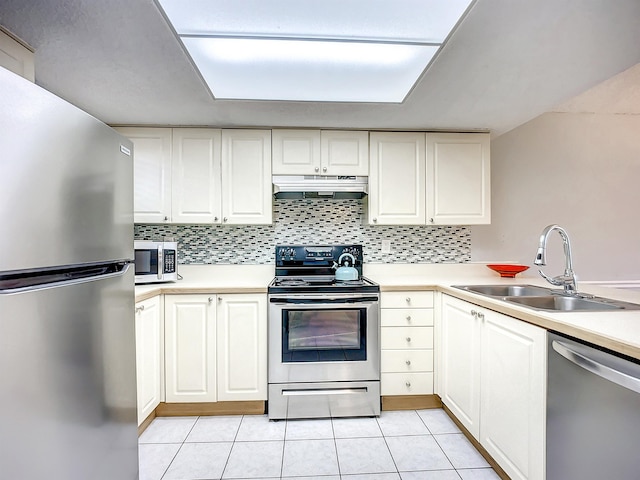 kitchen featuring appliances with stainless steel finishes, tasteful backsplash, sink, light tile patterned floors, and white cabinets