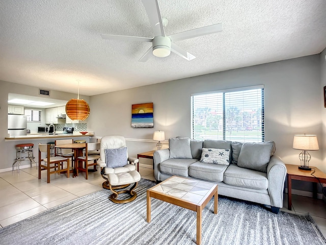 tiled living room with ceiling fan and a textured ceiling