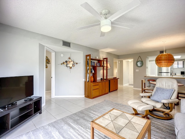 living room with light tile patterned floors, a textured ceiling, and ceiling fan